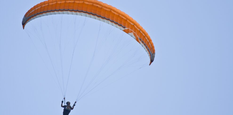 Amazing shot of a human paragliding on a blue sky background